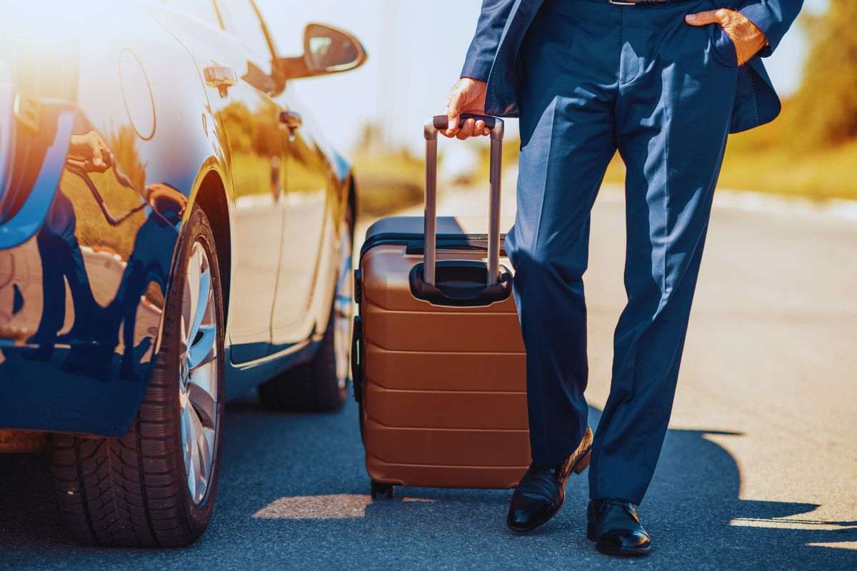 uomo con valigia che parte in auto