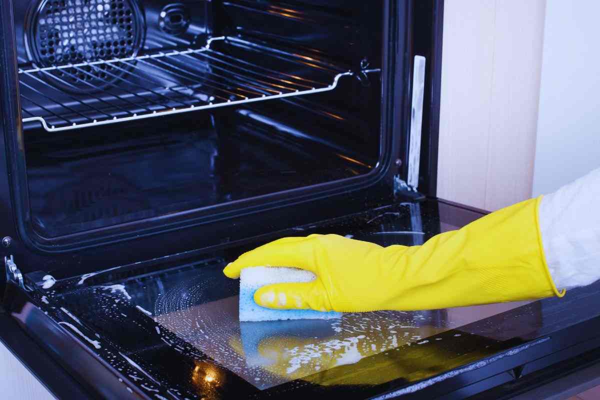 Donna che insapona lo sportello esterno del forno